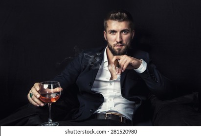 Attractive man with a cigar, and a glass of wine in his hands