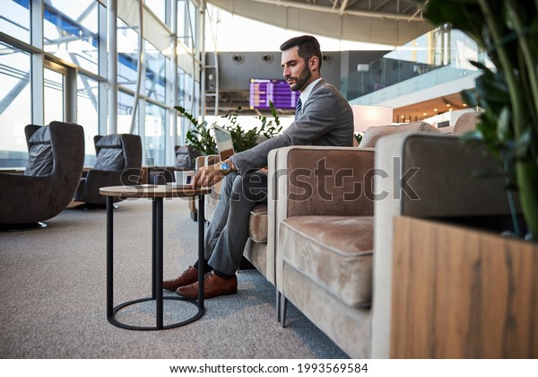 Attractive\
man with coffee and gadget in the airport\
hall