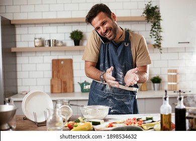 Attractive man cooking in modern kitchen. Handsome man talking to the phone while cooking.	 - Powered by Shutterstock