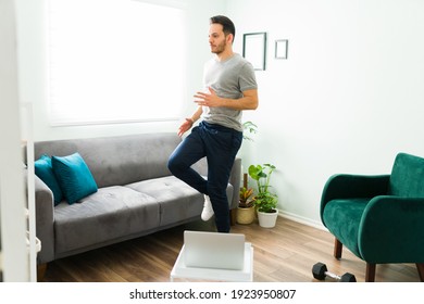 Attractive Man Doing A High Intensity Interval Training At Home. Young Man In Activewear Running In Place In The Living Room