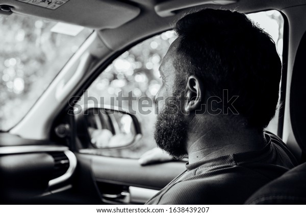 Attractive man in good car. Man with a beard in a\
car. A man with a beard in a car is not driving. The guy is a\
passenger in the car in the front seat. Portrait of a man. Do not\
distract the driver