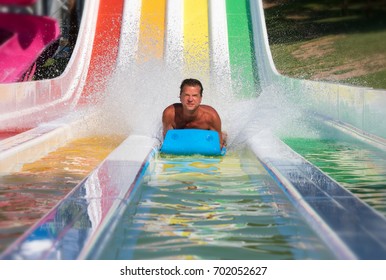 Attractive Man Is Having Fun On A Colorful Water Slide