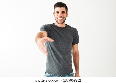 Attractive Man In His 20s Is Laughing With A Big Smile. Latin Guy Has His Arm Raised And Is Trying To Reach And Touch Something In Front Of Him