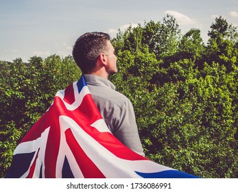 Attractive man holding Australian Flag on blue sky background on a clear, sunny day. View from the back, close-up. National holiday concept - Powered by Shutterstock