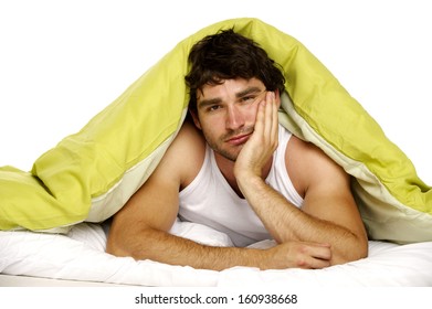 Attractive Man Laid In Bed Under A Green Duvet Looking Tired And Fed Up In The Morning