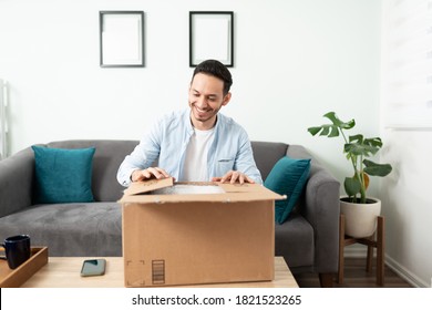 Attractive Man Looking Happy While Opening A Package With Some Of The Stuff He Bought Online