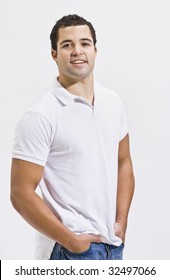 An Attractive Man Posing In Blue Jeans And A Polo Shirt. He Is Smiling Directly At The Camera. Vertically Framed Shot.