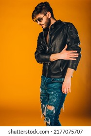 Attractive Man Posing In Ripped Blue Jeans And Fancy Leather Jacket