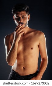 Attractive Man Posing Shirtless In Ripped Black Jeans And Smoking