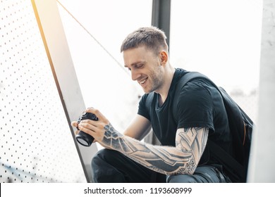 Attractive man sitting at staircase, smiling and checking photos in camera. - Powered by Shutterstock