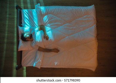 The Attractive Man Sleeping On The Bed At Night. View From Above