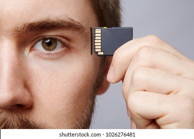 Attractive man at studio background, business concept, copy space, portrait, holding memory card, close up.