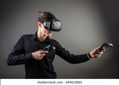 attractive man wearing virtual reality headset with two handheld trackpads or controllers