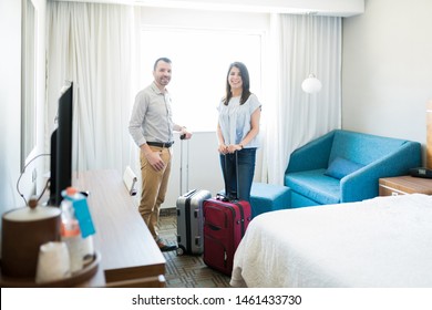 Attractive man and woman on vacation standing with suitcases by furniture while making eye contact in hotel room - Shutterstock ID 1461433730
