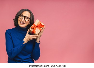 Attractive Mature Aged Aged Woman Holding Presents Gift Box Feels Happy Studio Isolated Over Pink Background. Life Events Celebration Congratulation Love Care Concept