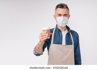 Attractive Mature Barman In Protective Mask Against Covid 19 Handing A Cup Of Hot Drink Isolated Over White Background