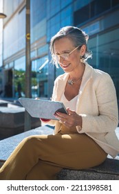 Attractive Mature Business Woman Happy Working With A Tablet In A Modern City. 