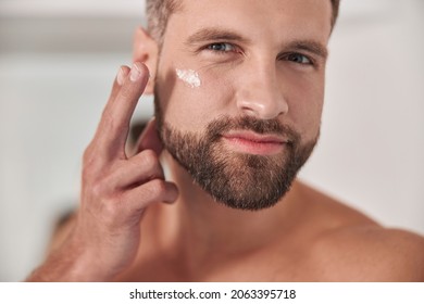 Attractive Mature Man Applies Cream Onto Skin Under Eye In Bathroom