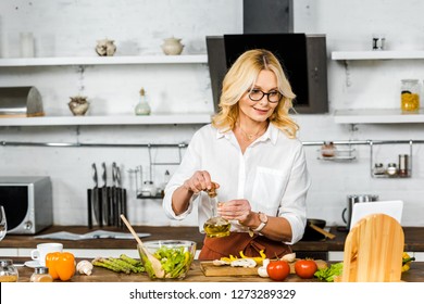 attractive mature woman reading recipe from tablet during cooking in kitchen - Powered by Shutterstock