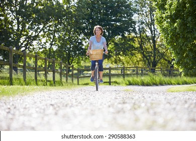 Attractive Mature Woman Riding Bike Along Country Lane