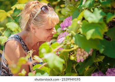 Attractive mature woman smelling beautiful pink hydrangea flowers outdoor - Powered by Shutterstock