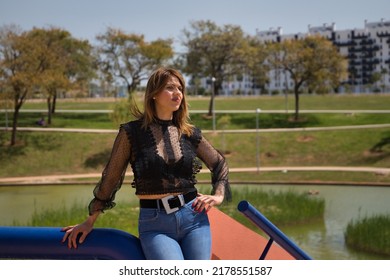 Attractive Mature Woman In Transparent Black Shirt And Jeans, Leaning On A Railing In Sensual And Provocative Attitude. Concept Maturity, Beauty, Fashion, Trend, Sensuality, Provocation.