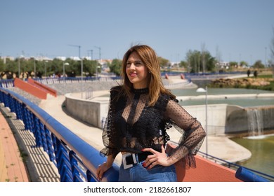 Attractive Mature Woman In Transparent Black Shirt And Jeans, Leaning On A Railing In Sensual And Provocative Attitude. Concept Maturity, Beauty, Fashion, Trend, Sensuality, Provocation.