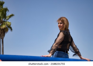 Attractive Mature Woman In Transparent Black Shirt And Jeans, Leaning On A Railing In Sensual And Provocative Attitude. Concept Maturity, Beauty, Fashion, Trend, Sensuality, Provocation.