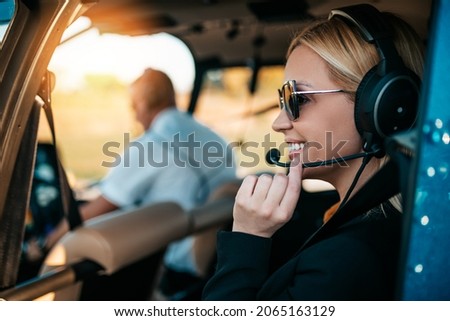 Attractive middle age business woman using private air transport chopper or helicopter to travel to a business meeting.
