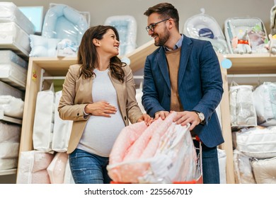 Attractive middle age couple enjoying in buying clothes and bed sheets for their new baby. Heterosexual couple in baby shop or store. Expecting baby concept. - Powered by Shutterstock