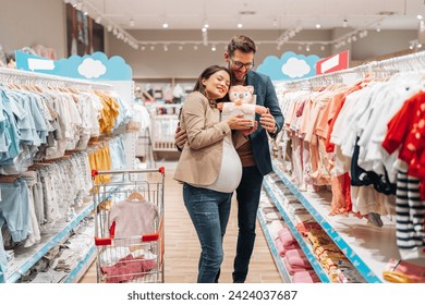 Attractive middle age couple enjoying in buying clothes and appliances for their new baby. Heterosexual couple in baby shop or store. Expecting baby concept. - Powered by Shutterstock