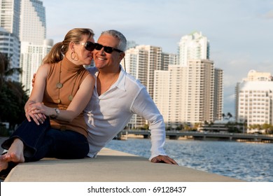 Attractive Middle Age Couple Posing Along The Bay Front With Condos In The Background.