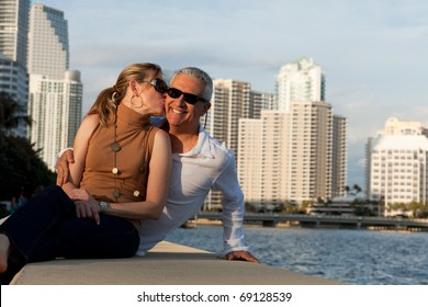 Attractive Middle Age Couple Posing Along The Bay Front With Condos In The Background.