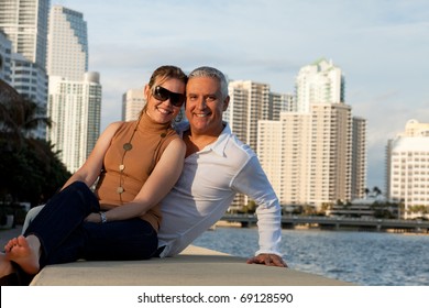 Attractive Middle Age Couple Posing Along The Bay Front With Condos In The Background.