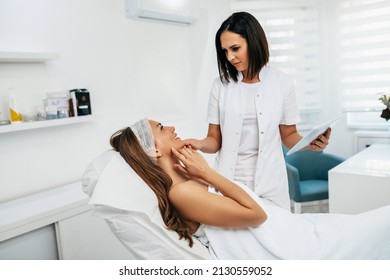 Attractive Middle Age Woman Talking With Doctor Specialist In Beauty Clinic About Skin Care And Face Treatments.