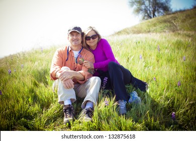 Attractive Middle Aged Couple Lying In The Tall Grass And Wild Lupine