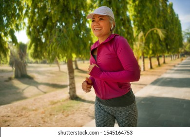 Attractive Middle Aged Lady Running Happy At City Park . Beautiful And Sporty Woman On Her 40s Exercising Doing Jogging Workout On A Sunny Morning Enjoying Healthy Lifestyle And Fitness