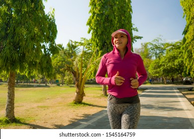 Attractive Middle Aged Lady Running Happy At City Park . Beautiful And Sporty Woman On Her 40s Exercising Doing Jogging Workout On A Sunny Morning Enjoying Healthy Lifestyle And Fitness