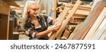 Attractive middle aged woman carpenter designer works with ruler, make notches on the tree in workshop. Image of modern femininity. Concept of professionally motivated women