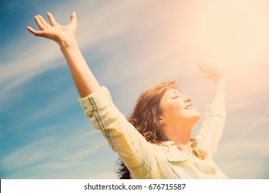 Attractive Middle Aged Woman Enjoying The Sun And Nature With Outstretched Arms. Freedom Concept.