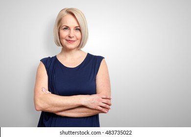 Attractive middle aged woman with folded arms on grey background - Shutterstock ID 483735022