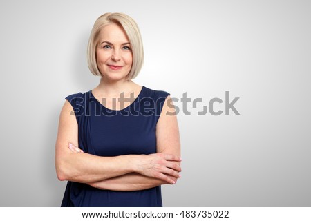 Attractive middle aged woman with folded arms on grey background
