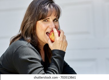 Attractive Middle Aged Woman Holding An Apple In Her Hand Preparing To Bite It