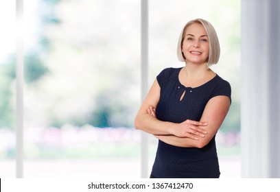 Attractive Middle Aged Woman Smiles emotionally stands near the window at home - Powered by Shutterstock