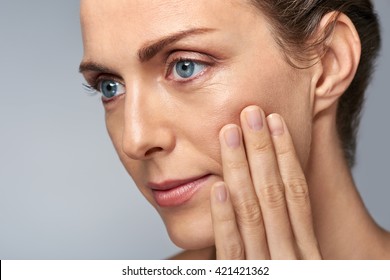 Attractive middle aged woman touching her cheek skin, mature beauty concept - Shutterstock ID 421421362