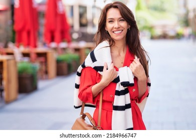 Attractive Middle Aged Woman Walking On The Street While Looking At Camera And Smiling. 