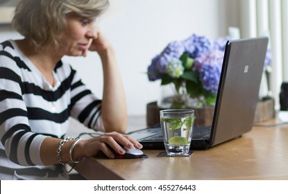 Attractive middle-aged blonde businesswoman working, using portable computer, looking at the monitor - Powered by Shutterstock