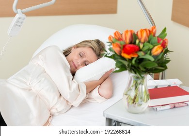 Attractive middle-aged female patient lying sleeping peacefully in a hospital bed as she recuperates from an injury, surgery or illness - Powered by Shutterstock