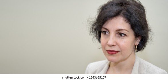 Attractive Middle-aged Successful Women With Beautiful Smile In Business Suit Against Concrete Beige Wall, Head And Shoulders Portrait With Copy Space.