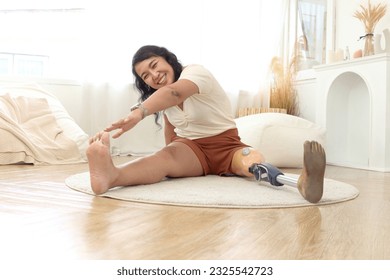 Attractive middle-aged woman with prosthetic leg doing exercise at home, happy disabled Asian female doing stretching on floor, cheerful sporty woman with disability doing warm-up before workout. - Powered by Shutterstock